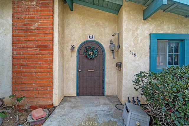 doorway to property with brick siding and stucco siding