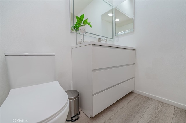 bathroom featuring vanity, wood finished floors, toilet, and baseboards