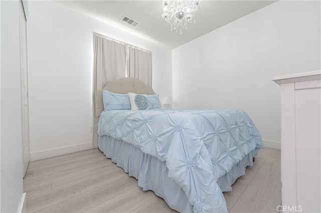 bedroom with light wood finished floors, baseboards, visible vents, and an inviting chandelier