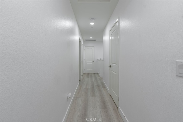 hallway featuring light wood-type flooring, baseboards, and recessed lighting