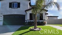 view of front facade with aphalt driveway, an attached garage, fence, a front yard, and stucco siding