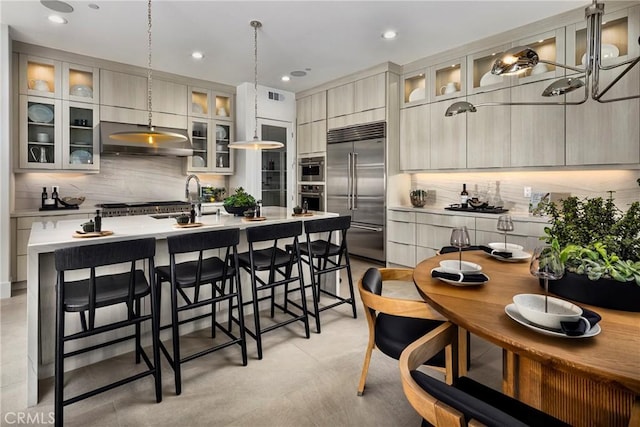 kitchen with visible vents, an island with sink, light countertops, appliances with stainless steel finishes, and backsplash