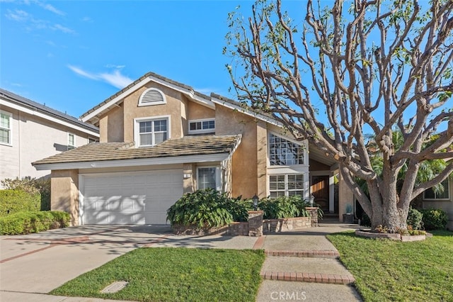 traditional-style house featuring driveway, a front lawn, an attached garage, and stucco siding