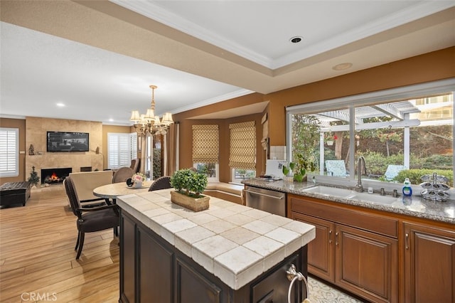 kitchen featuring ornamental molding, a center island, a sink, a fireplace, and stainless steel dishwasher