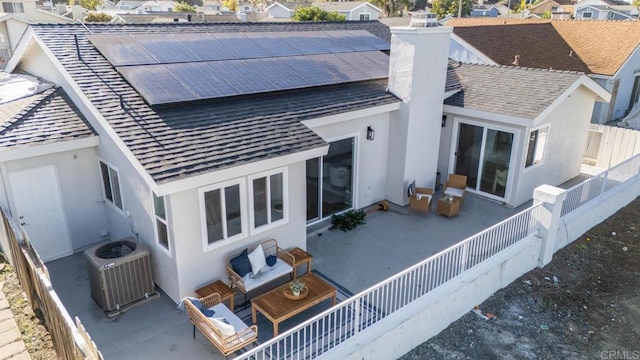 rear view of property with solar panels, a patio area, central AC unit, and stucco siding