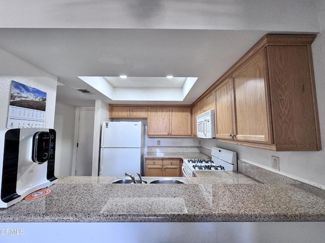 kitchen featuring white appliances, visible vents, a raised ceiling, a peninsula, and a sink