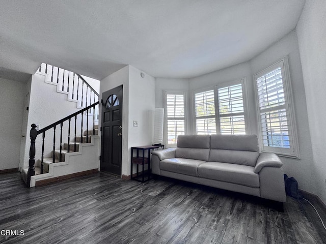 living area with stairs, dark wood-style flooring, baseboards, and a healthy amount of sunlight