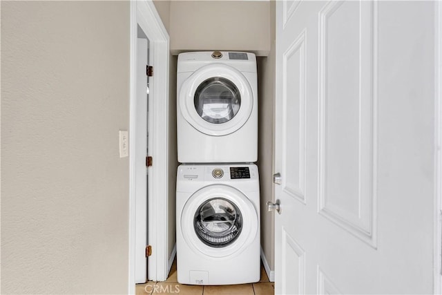 laundry room featuring stacked washer and dryer, laundry area, and light tile patterned flooring