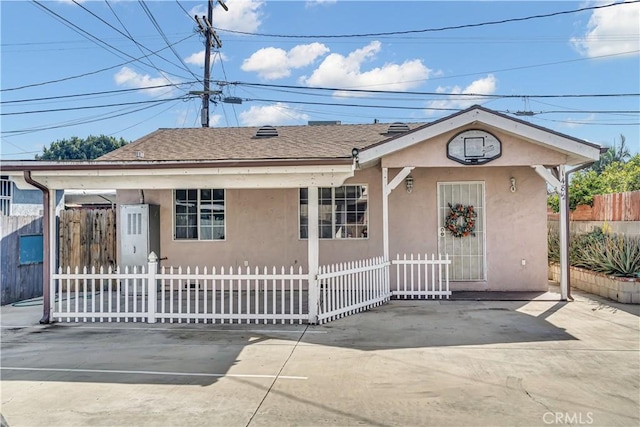 view of front of property with a fenced front yard, roof with shingles, driveway, and stucco siding