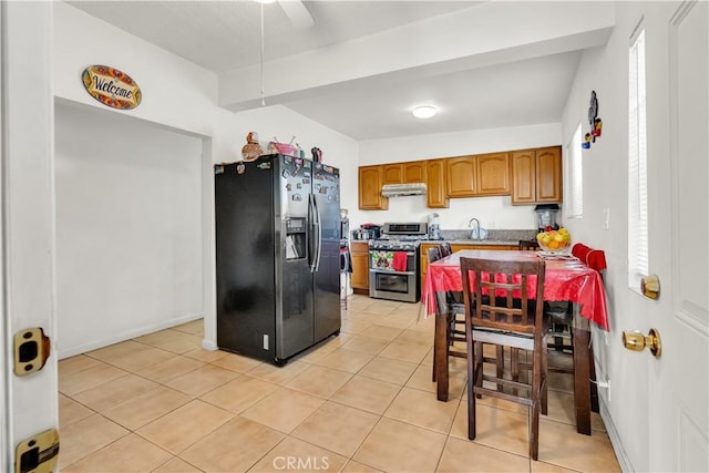 kitchen with light tile patterned floors, appliances with stainless steel finishes, brown cabinetry, a sink, and under cabinet range hood