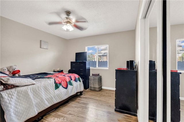 bedroom with light wood-style flooring, multiple windows, baseboards, and a textured ceiling