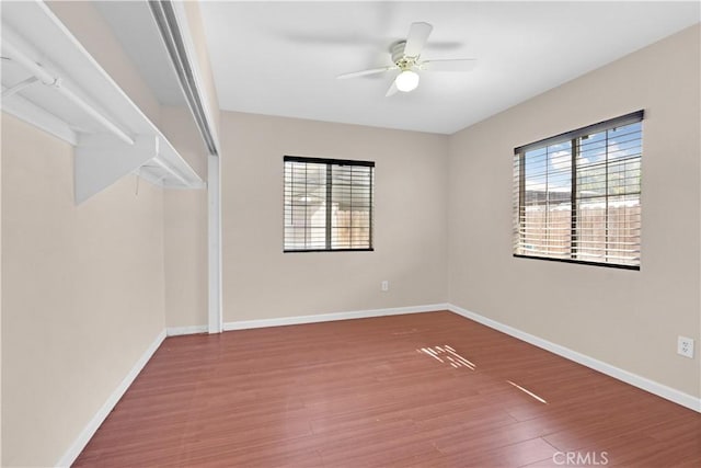 unfurnished room with a ceiling fan, baseboards, and wood finished floors