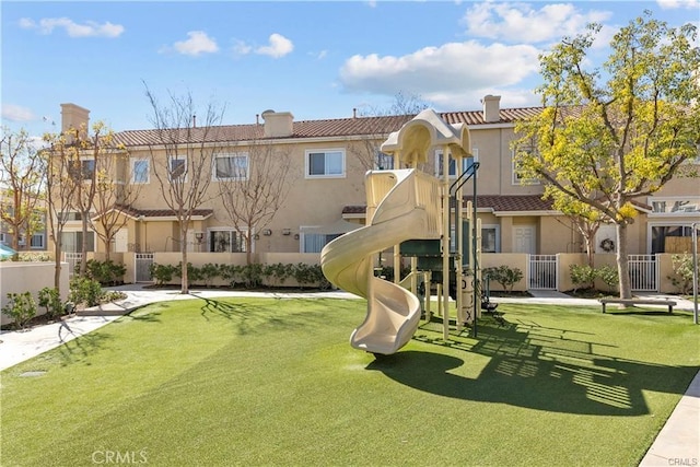 communal playground with a lawn, fence, and a residential view