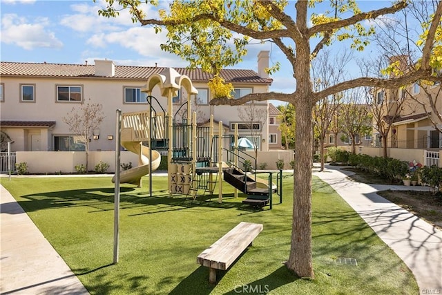 view of play area featuring a lawn, fence, and a residential view