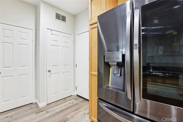 kitchen with light wood-style floors, light brown cabinetry, stainless steel fridge, and visible vents