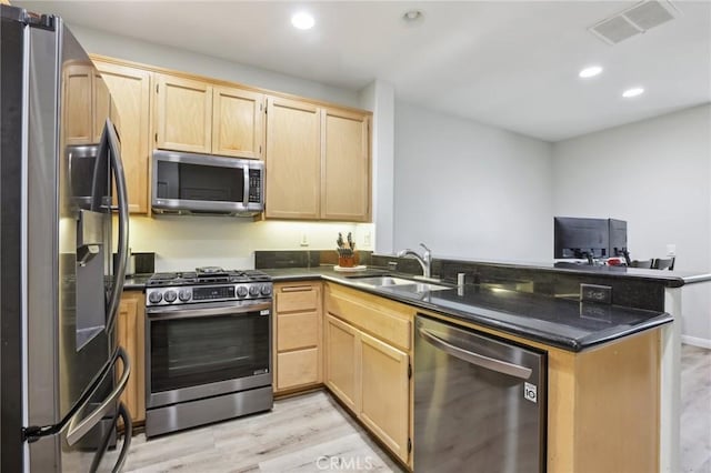kitchen with light brown cabinets, a peninsula, visible vents, appliances with stainless steel finishes, and a sink