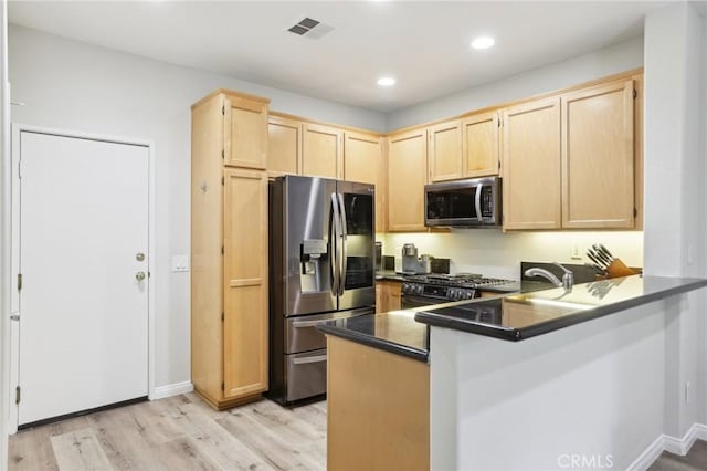 kitchen with light brown cabinetry, appliances with stainless steel finishes, a peninsula, and visible vents