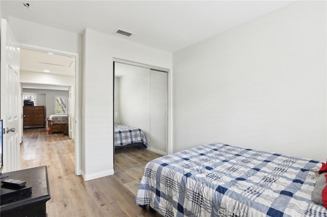 bedroom featuring light wood-style floors, visible vents, a closet, and baseboards