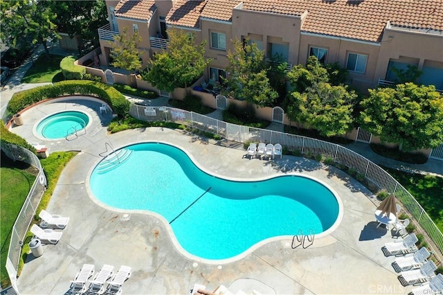 community pool featuring a patio, fence, and a hot tub