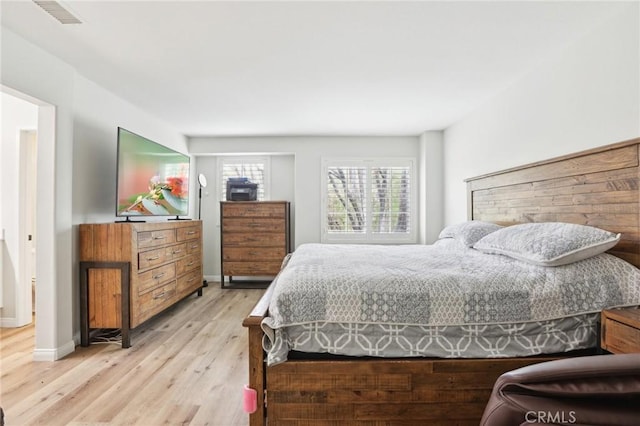 bedroom with light wood finished floors, visible vents, and baseboards