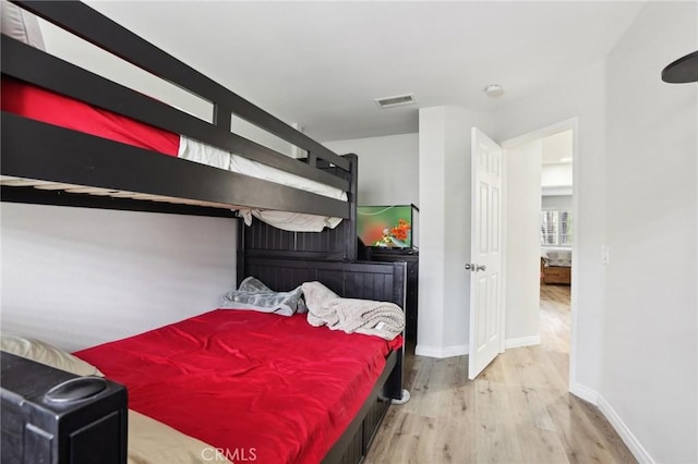 bedroom with visible vents, baseboards, and wood finished floors