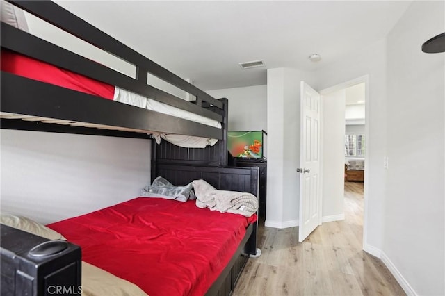 bedroom with visible vents, baseboards, and wood finished floors