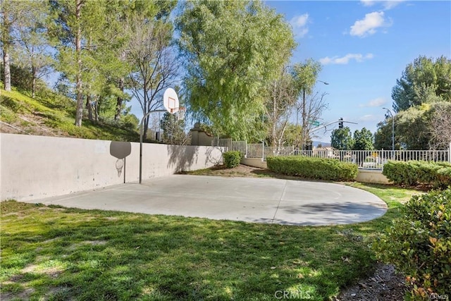 view of basketball court with community basketball court, fence, and a lawn