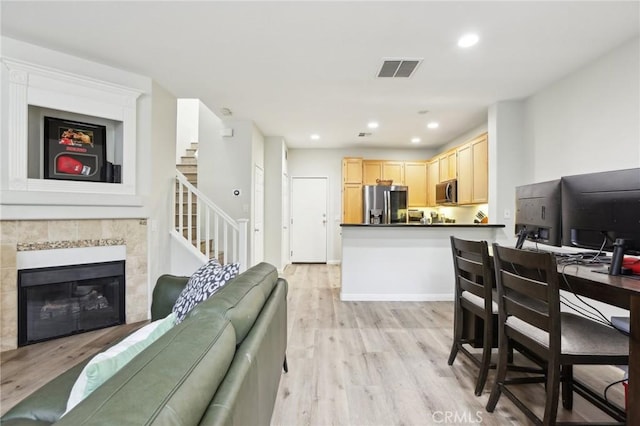 living room with a fireplace, recessed lighting, visible vents, light wood-style flooring, and stairs