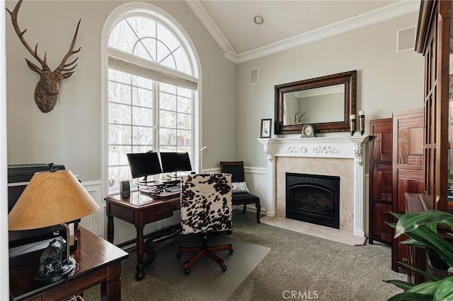 office featuring light carpet, a fireplace with flush hearth, visible vents, wainscoting, and crown molding