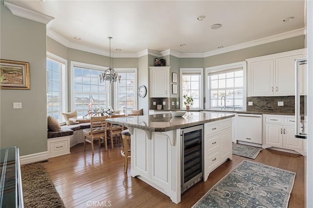 kitchen featuring white cabinets, dark wood finished floors, wine cooler, a kitchen island, and white dishwasher