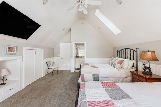 carpeted bedroom featuring vaulted ceiling with skylight, ceiling fan, a closet, and wainscoting