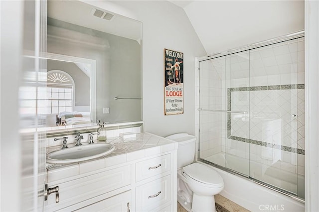 bathroom with toilet, vanity, visible vents, vaulted ceiling, and combined bath / shower with glass door