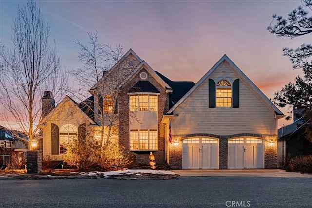 view of front of house featuring an attached garage, driveway, and brick siding