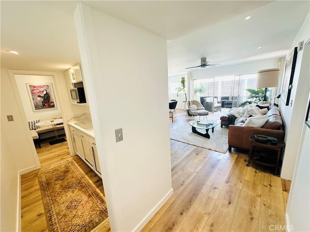 corridor featuring light wood-type flooring and baseboards