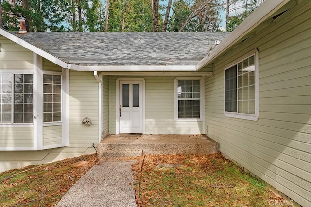 property entrance featuring a patio and a shingled roof