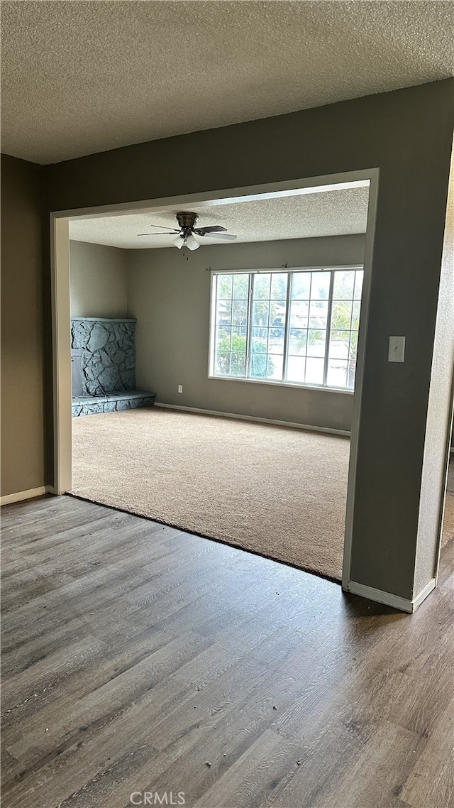 empty room featuring ceiling fan, a textured ceiling, baseboards, and wood finished floors