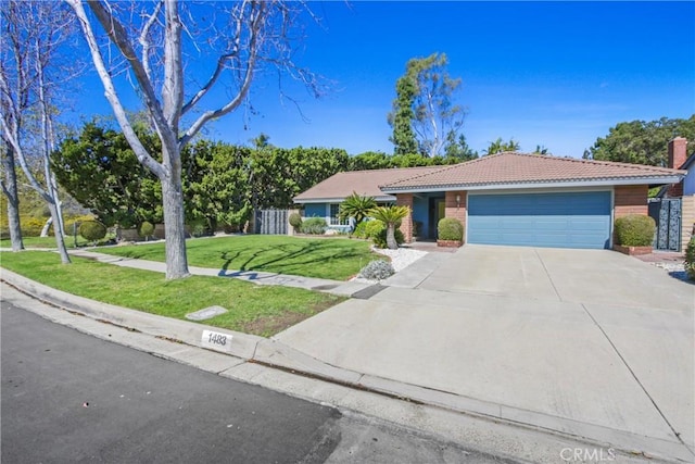 ranch-style house with fence, a garage, driveway, a tiled roof, and a front lawn