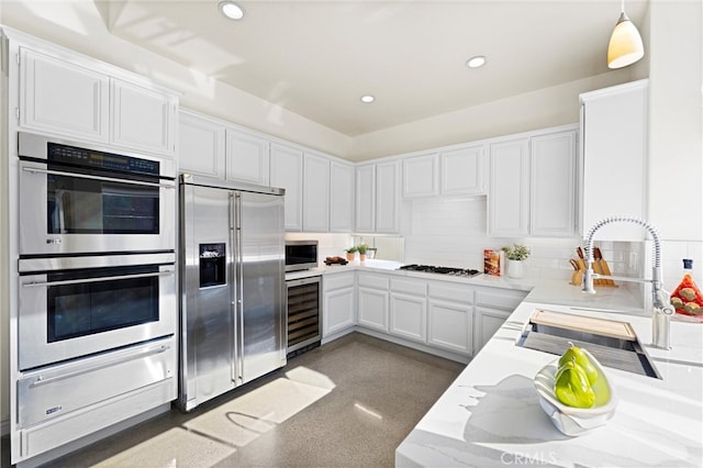 kitchen with wine cooler, a sink, appliances with stainless steel finishes, decorative backsplash, and a warming drawer