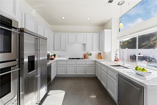 kitchen featuring stainless steel appliances, recessed lighting, backsplash, white cabinets, and a sink