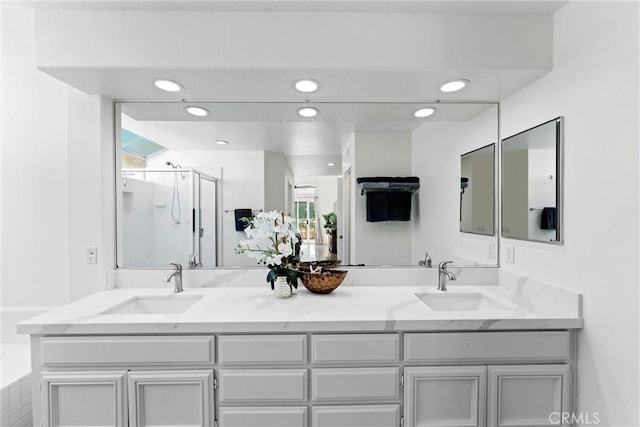 bathroom featuring a sink, a shower stall, and double vanity