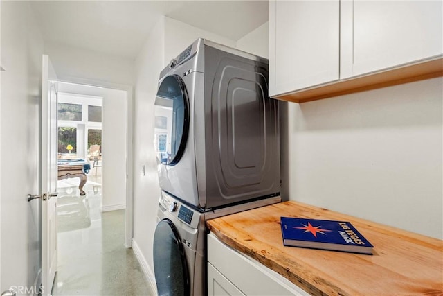 clothes washing area with cabinet space and stacked washer and clothes dryer