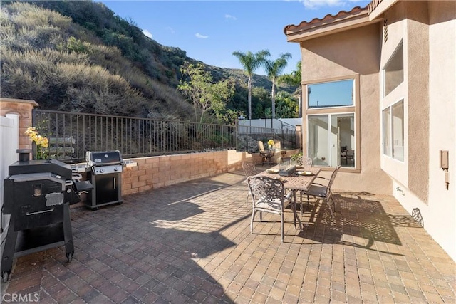 view of patio with outdoor dining space, fence, and area for grilling