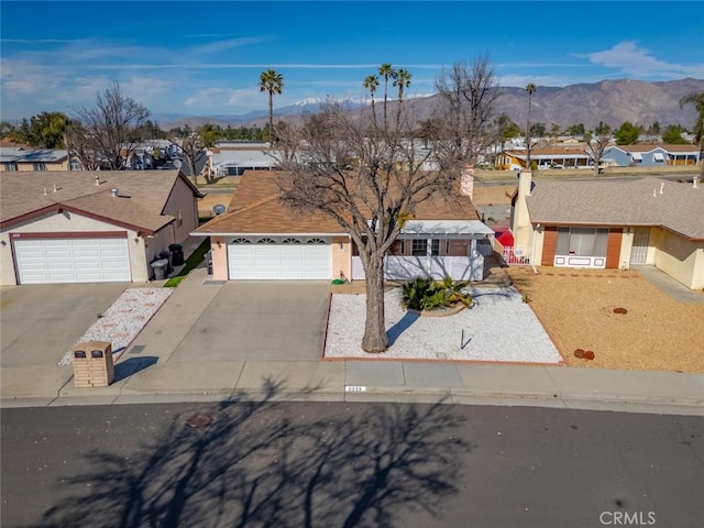 ranch-style house with a mountain view, a garage, concrete driveway, a residential view, and stucco siding