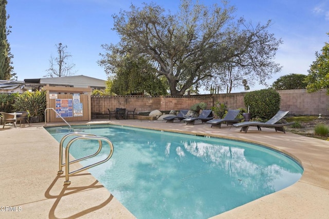 community pool featuring a fenced backyard and a patio