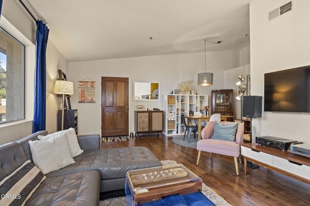 living room with dark wood-style floors, visible vents, and vaulted ceiling