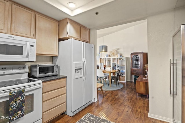 kitchen featuring dark countertops, white appliances, a toaster, and light brown cabinetry