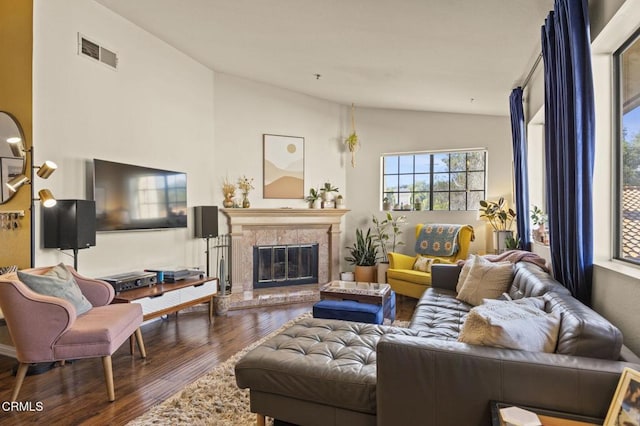 living room with lofted ceiling, visible vents, dark wood finished floors, and a high end fireplace