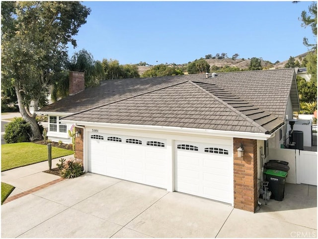 exterior space with brick siding, driveway, a chimney, and an attached garage