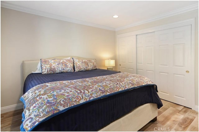 bedroom with ornamental molding, a closet, wood finished floors, and baseboards