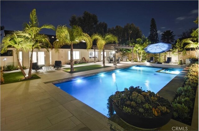 pool at night with an outdoor pool, a patio area, and a pergola